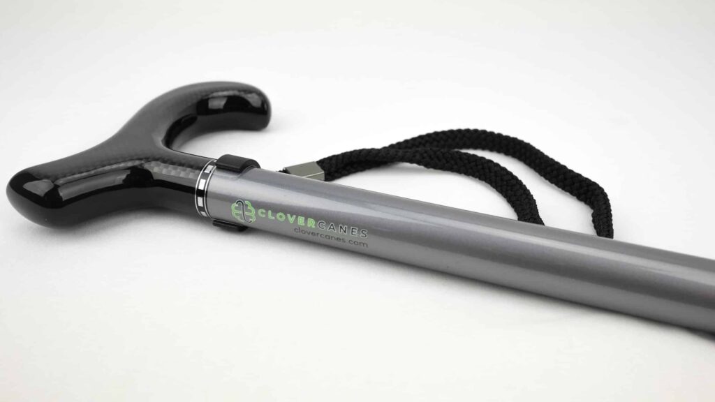 Close-up of a gray mobility cane with a glossy black handle and a black woven strap, showing the CloverCanes logo.